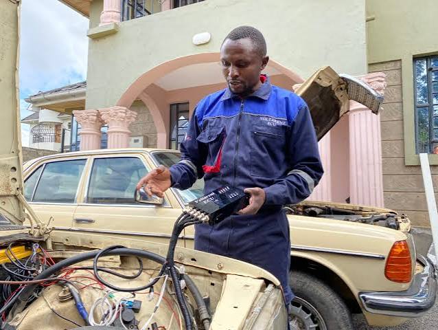 Glambo Garage technician working on a vehicle's electronics and ECU